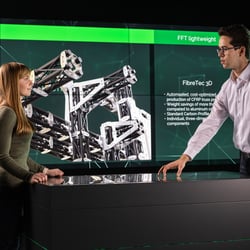 Marketing und Vetrieb unterhalten sich vor Screen-Wall im B2B Showroom