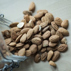 Almonds spilled on wooden background.