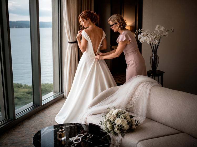 Braut und Brautmutter beim Anziehen des Brautkleides hoch über dem Genfersee