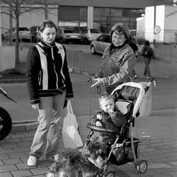 Drei Generationen mit Hund auf einem Parkplatz
