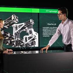 Marketing und Vetrieb unterhalten sich vor Screen-Wall im B2B Showroom