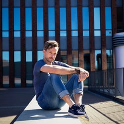 Outdoor-Portrait mit urbanem Hintergrund. Natürliches Tageslicht, entspannte Pose. Aufgenommen in Dortmund