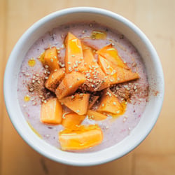 Raspberry porridge with persimmon fruit, sesame seeds and linseed oil.