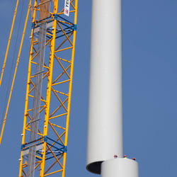 Turmteile in der Montage, dazwischen drei Monteure