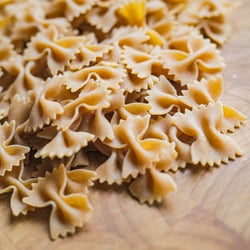 Organic whole grain Farfalle on wooden kitchen worktop.