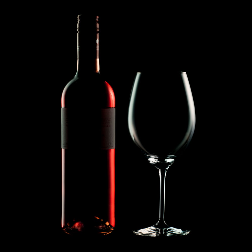 Weinflasche und Glas vor Schwarz