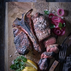 Marius Prions Photo FOOD / T-Bone Steak, auf Holzbrett, geschnitten