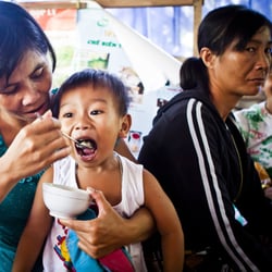 A child being fed at a nutrition support group meeting sponsored by UNICEF